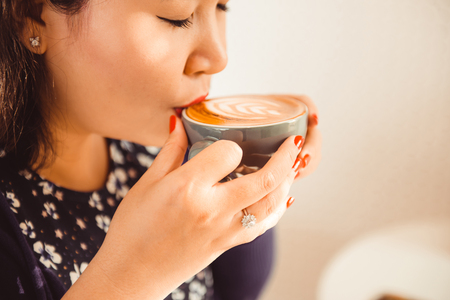 Closeup of asian woman sitting in a cafe and drink coffeeの写真素材