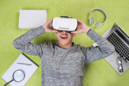 Top view of asian man wearing virtual reality goggles. Man lying on the floor.の写真素材