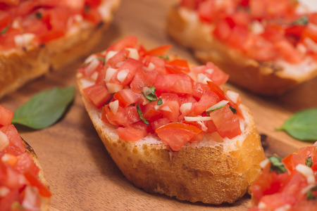 Tasty Italian bruschetta with  bread topped with tomato and herbs on wooden boardの写真素材