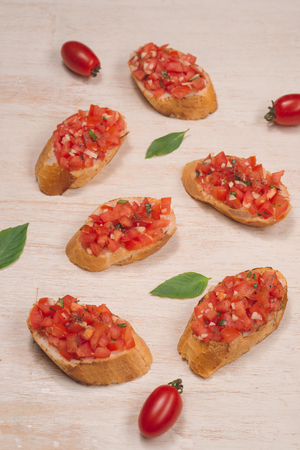 Tasty Italian bruschetta with  bread topped with tomato and herbs on wooden boardの写真素材