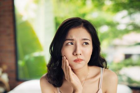 Asian young woman with teeth hurt at home.の写真素材