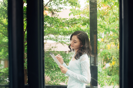 Young attractive sweet girl with notepad on a veranda. Spring mood.の写真素材