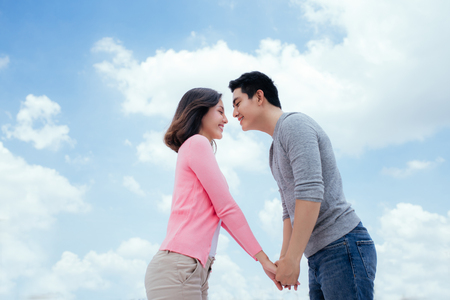 Young beautiful woman and asian man laugh against the dark blue sky with cloudsの写真素材