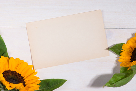 Yellow flowers and empty paper for your text on wooden backgroundの写真素材