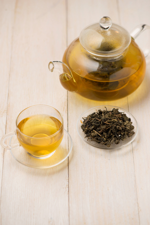 Pouring tea. Cup of hot tea and tea leaf on the wooden tableの写真素材