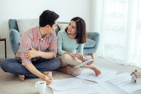 Attractive young asian adult couple looking at house plans.の写真素材
