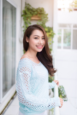 Young asian woman relaxing on a balcony  enjoying fresh air.の写真素材