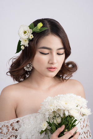 Beautiful asian woman bride on grey background. Closeup portraits with a professional makeupの写真素材