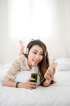 Woman Relaxing in bed and listening to music, relaxing in her living roomの写真素材