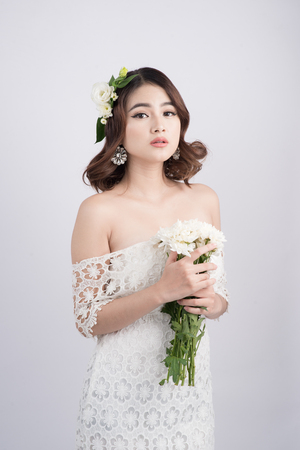 Beautiful asian woman bride on grey background. Closeup portraits with a professional makeupの写真素材