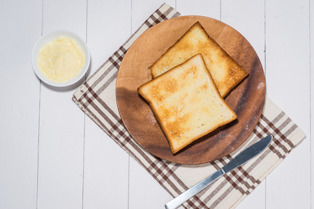 Close-up of slice of toast bread with butter on wood tableの写真素材
