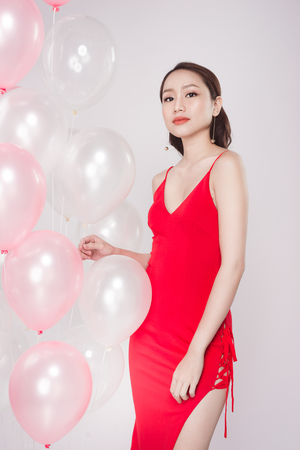 Asian beautiful woman in red dress with pastel balloonsの写真素材