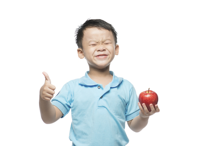 Asian baby boy holding and eating red apple, isolated on whiteの写真素材