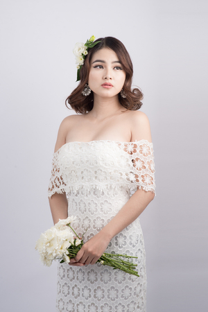 Beautiful asian woman bride on grey background. Closeup portraits with a professional makeupの写真素材