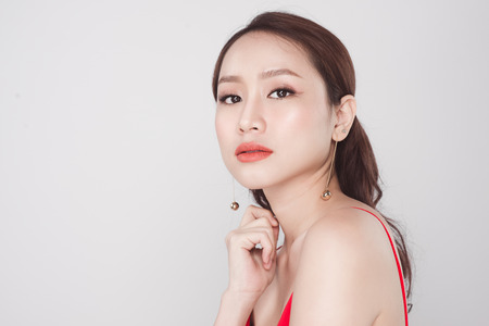 Portrait of stylish asian woman wearing red dress on grey background.の写真素材