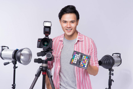 Young asian photographer holding digital camera, while working in studioの写真素材