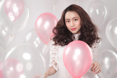 Asian pretty fashionable woman in white dress with pastel balloonsの写真素材