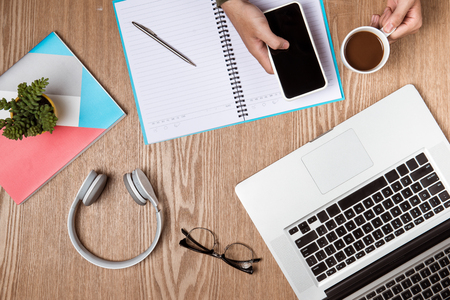 Business man hands using a laptop with a cup of coffee and smart phone with copy space.の写真素材