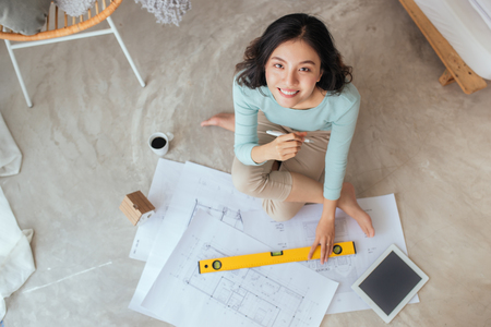 Happy pretty housewife holding new house interior sketch paperの写真素材