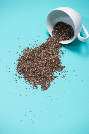 Nutritious chia seeds in cup on light blue background.の写真素材