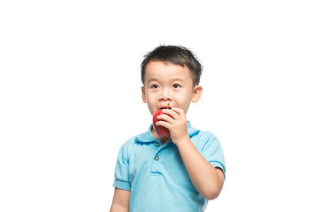 Asian baby boy holding and eating red apple, isolated on whiteの写真素材