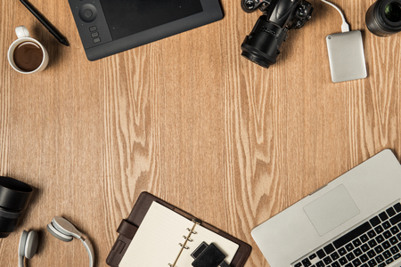 Work space for photographer, graphic designer. Flat lay of laptop, camera, colorchart, digital tablet, coffee cup, book, pencil on wooden table.の写真素材