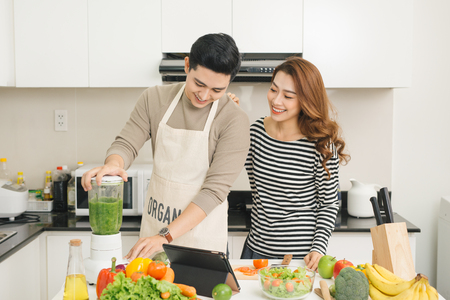 Portrait of happy asian young couple cooking together in the kitchen at home.の写真素材