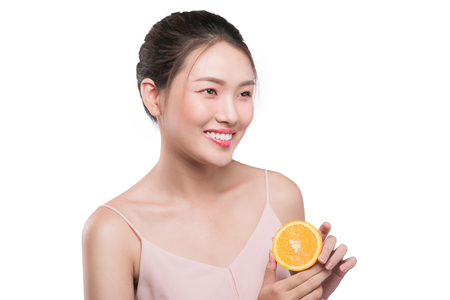 Portrait of lovely asian girl with black hair holding orangeの写真素材