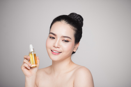 Beauty concept. Asian pretty woman with perfect skin holding oil bottleの写真素材