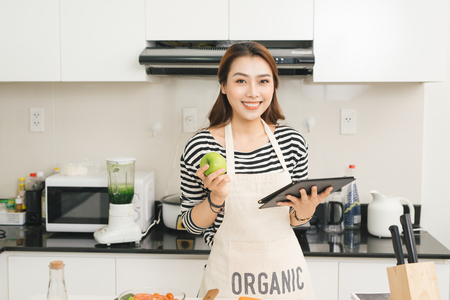 Young asian woman using a tablet computer to cook in her kitchenの写真素材