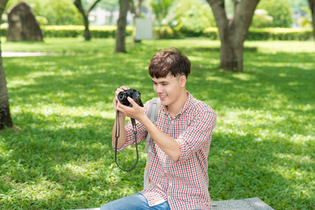 Young smiling man taking picture in the parkの写真素材