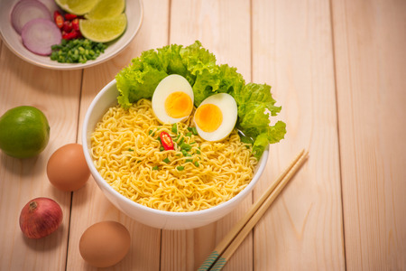 Instant noodles in bowl with vegetables and  boiled egg on wood backgroundの写真素材