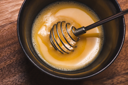 Prepare breakfast from eggs. Whipped eggs on wooden table.の写真素材