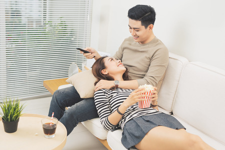Young couple with popcorn on the sofa watching a movieの写真素材