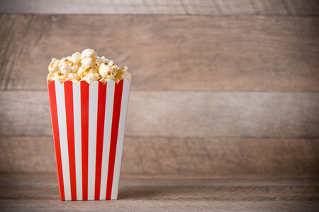 Popcorn in red and white cardboard on wooden table.の写真素材
