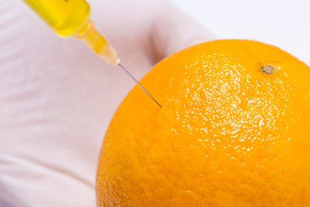 Science experiment with orange and syringe isolated on white.の写真素材