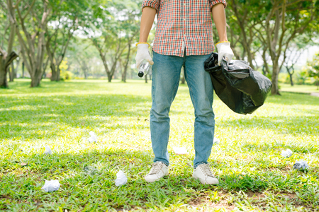 Cropped image of a man holding glass bottles and bin bagの写真素材