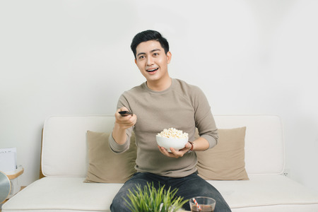 Young handsome man watching TV on the couch at homeの写真素材