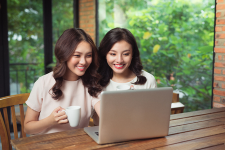 Young female friends surfing the internet together on a laptopの写真素材