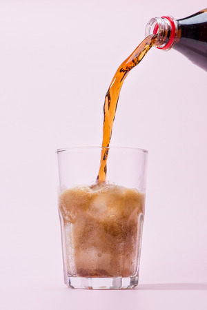 Pouring cola from bottle into glass with splashingの写真素材