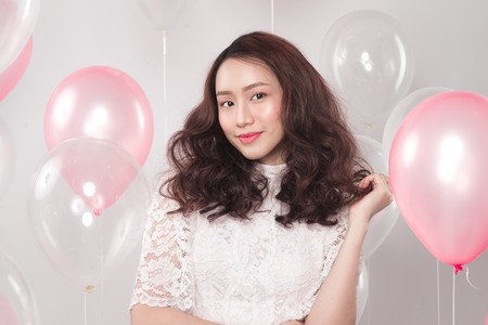 Asian pretty fashionable woman in white dress with pastel balloonsの写真素材