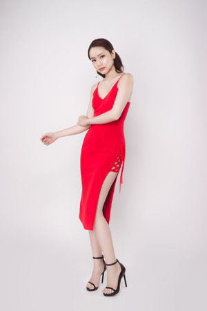 Beautiful stylish asian woman wearing red dress on grey background.の写真素材