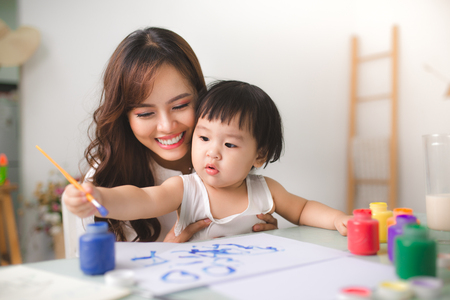Happy family mother and daughter together paint. Asian woman helps her child girl.の写真素材