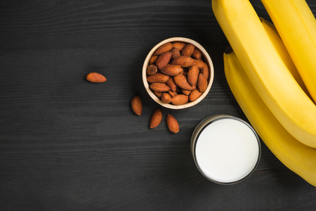 A banch of bananas with almonds and milk on wooden background.の写真素材
