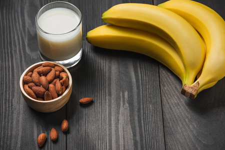 A banch of bananas with almonds and milk on wooden background.の写真素材