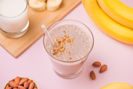 Fresh made banana smoothie in a glass on pink backgroundの写真素材