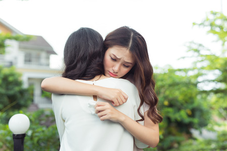 Friendship help support. Depressed asian woman embracing her friend.の写真素材