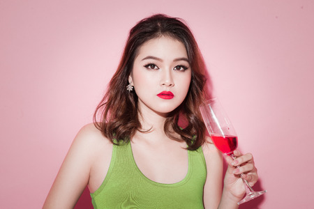 Celebrating asian girl with professional makeup holding a glass of champagne.の写真素材