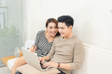 Happy asian couple in love surfing on laptop at homeの写真素材