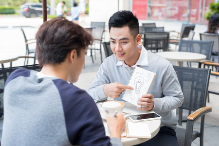 Two cheerful asian business people discussing with documentsの写真素材
